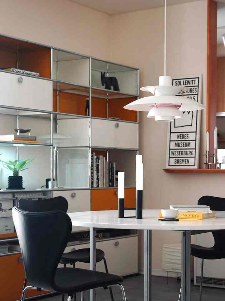 白とオレンジの色調のダイニング、丸いテーブルと黒いダイニングチェアが配置されたモダンで北欧風な印象的な空間