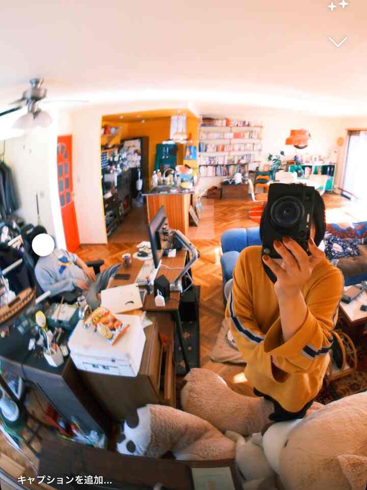 Bright light brown floored living room featuring blue sofa, desk, and bookshelf arranged in a cozy home office setting