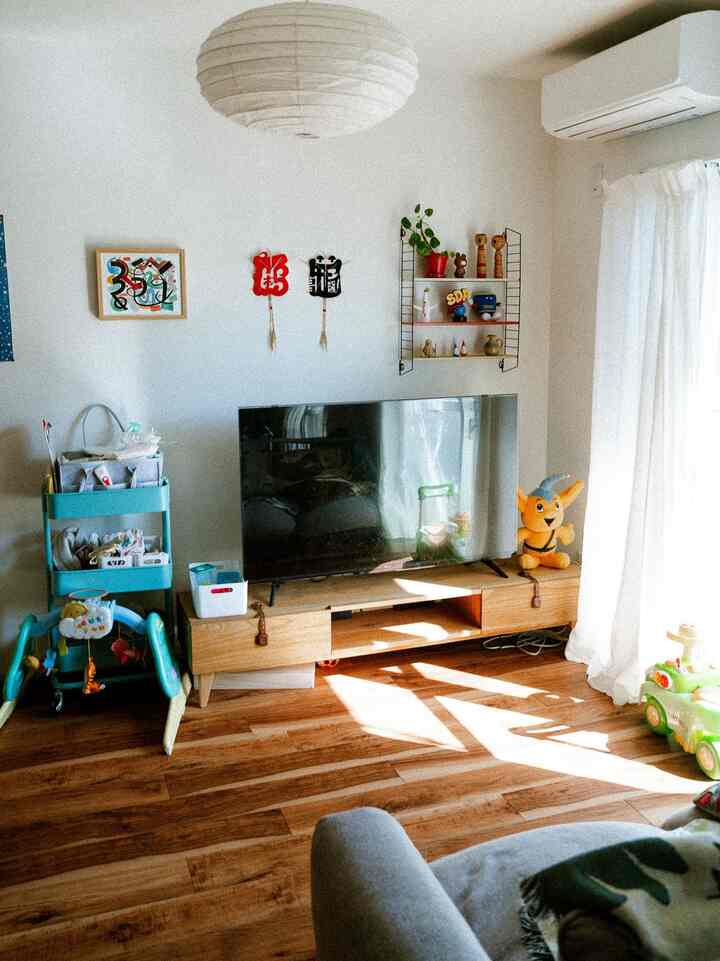 White-walled, wood-toned Nordic living room with a TV stand, designed as a child-friendly space