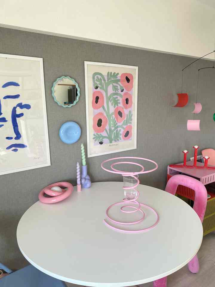 グレーの壁とピンクの椅子がある4人用の丸いダイニングテーブルが配置された居心地の良いダイニングルームのインテリア