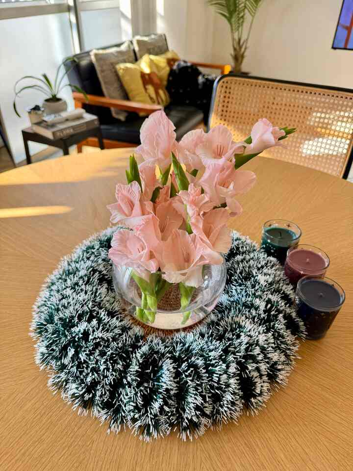 ウッドトーンのダイニングテーブルにピンクの花瓶とキャンドルが配置されたナチュラルでシンプルなリビング