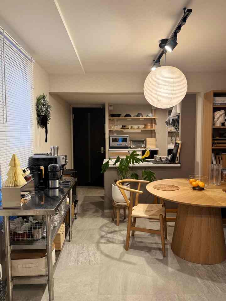 ナチュラルな木目調と白いペンダントライトが配置された、北欧風の2人用テーブルと植物のあるダイニングスペース