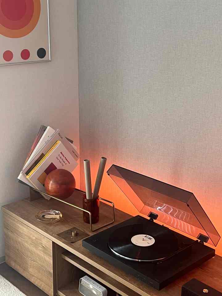 ウッドトーンの家具とレトロなLPプレーヤー、アートポスターがある温かみのあるモダンなインテリア空間