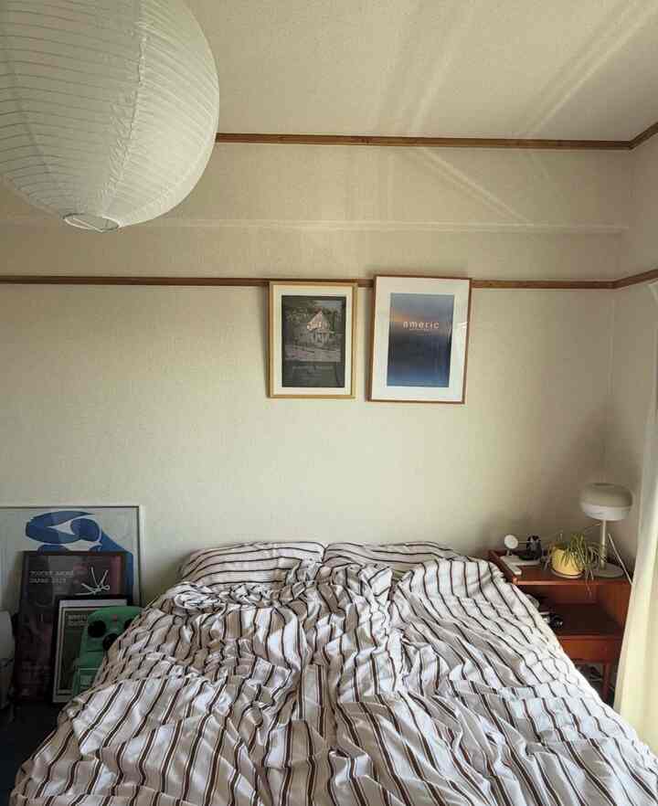 Natural-toned 6-tatami bedroom featuring a central double bed with striped bedding and a wooden dresser on the right, cozy atmosphere