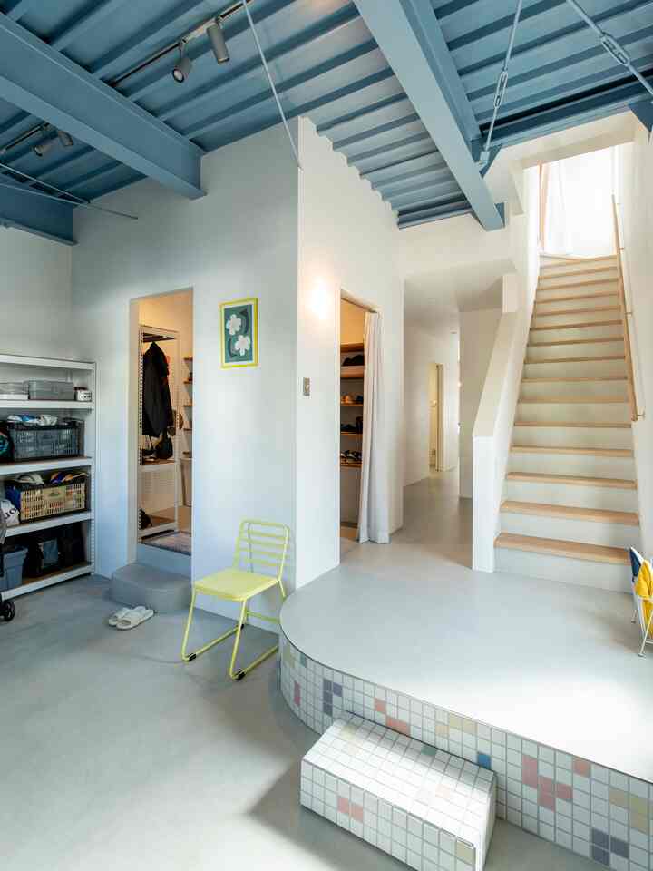 Pastel-toned entrance space featuring stairs and storage shelves with a minimal and tidy interior design