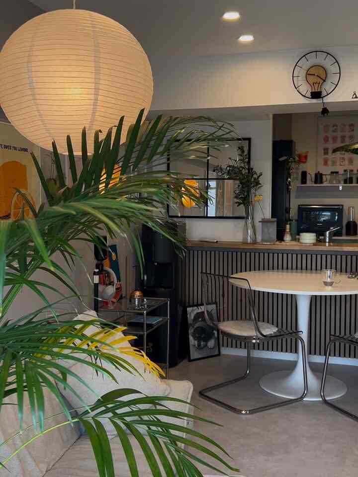 アイボリーのソファと緑のアレカヤシがある北欧風リビング、柔らかな光とミッドセンチュリーモダンのデザインが印象的な空間