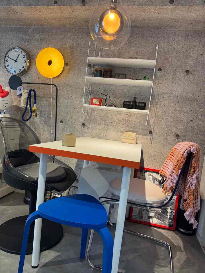 Compact single household space with dark gray concrete wall, white table, transparent chair, and blue stool