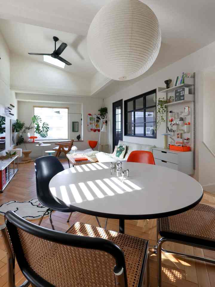 白と自然な木目調が調和するミッドセンチュリーモダンのリビング、オレンジのアクセントチェアが印象的な明るく開放的な空間