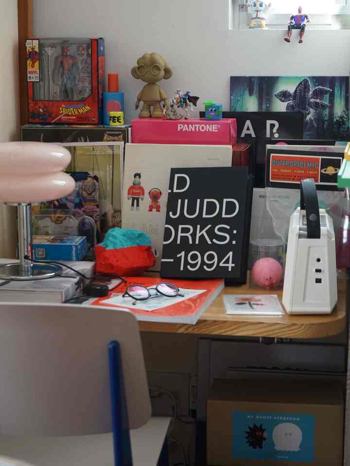 ナチュラルカラーの一人暮らし用ホームオフィス、木製デスクと白いオフィスチェア、そして多様なアートオブジェが配置された作業空間