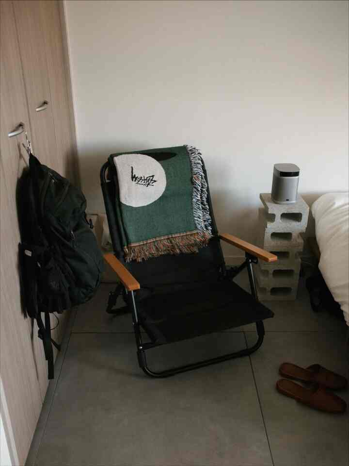 Small single household space in natural and white tones featuring a black armchair with wooden armrests in a simple interior