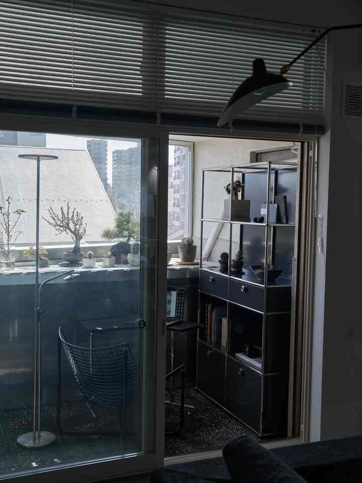 黒を基調としたベランダ、USM収納棚とIKEAのアームチェアが配置された植物に囲まれたモダンで落ち着いたインテリア