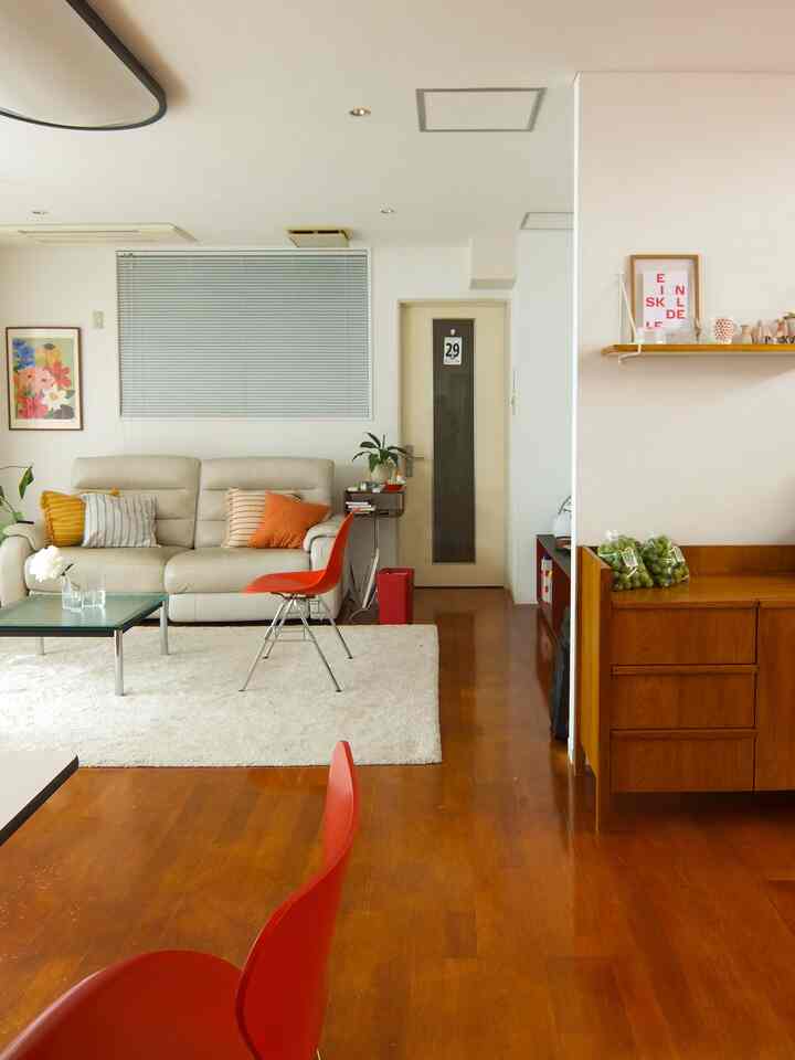 Bright mid-century modern living room with white and wood tones, featuring red chairs and cream sofa in a cozy atmosphere