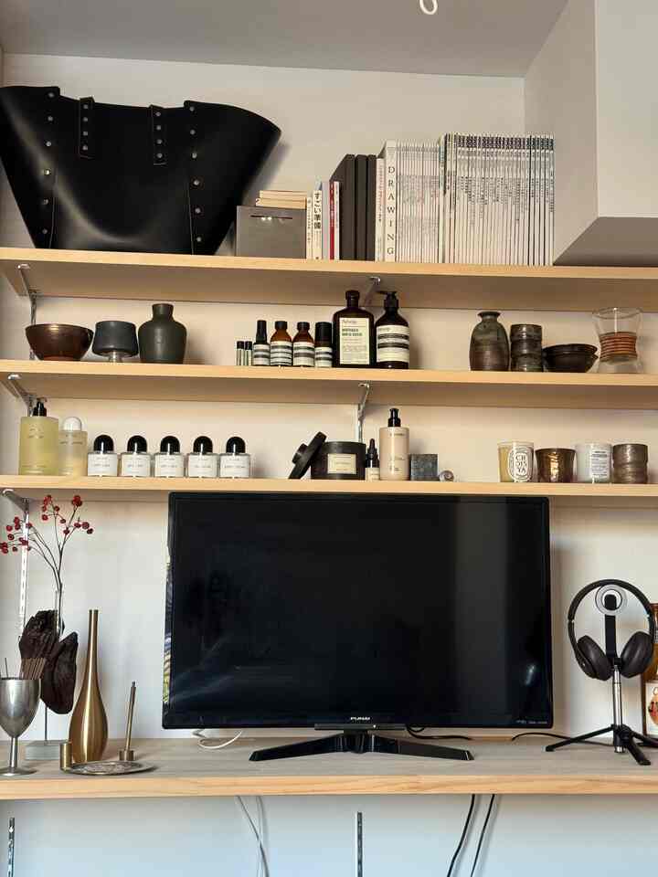 Cozy single household living room with natural wood tone shelves and a black TV centerpiece