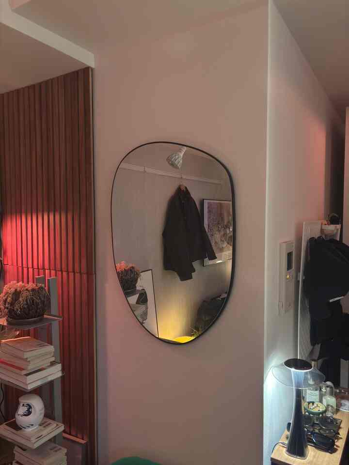 Warm wood tones and white in an 8-tatami studio entrance with an irregular wall-mounted mirror and indirect lighting enhancing the atmosphere