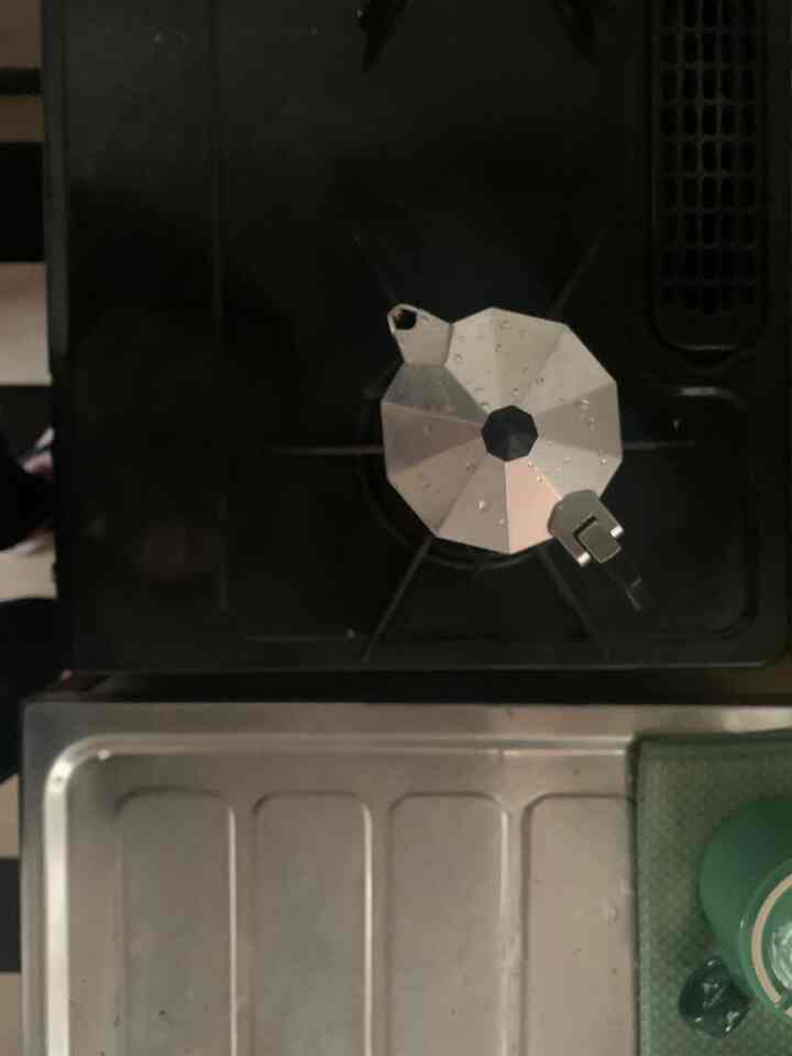 黒いガスコンロの上に銀色のエスプレッソメーカーが置かれたキッチンの空間