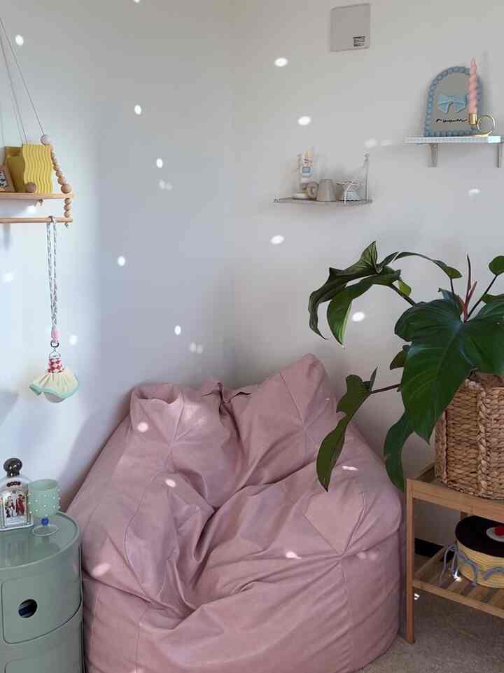 ピンク色のビーズクッションソファと白い壁、植物が配置された子供部屋のリラックススペース