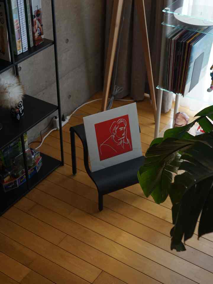 温かみのある木目調の床とモダンな家具が調和する一人暮らしの1LDK空間、スツールと本棚が配置された落ち着いた雰囲気のインテリア