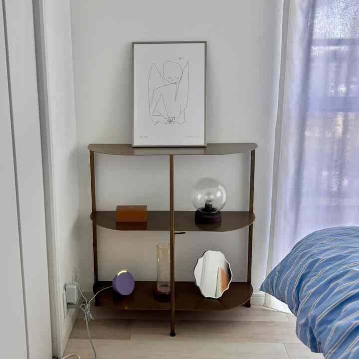 ゴールドトーンの寝室の棚と青のストライプ柄の掛け布団カバーが配置された落ち着いた雰囲気のインテリア