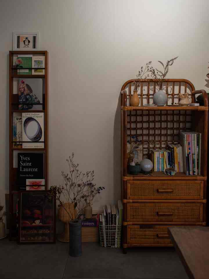 Natural brown toned studio living room featuring antique rattan cabinet, bookshelf, and vases creating cozy atmosphere