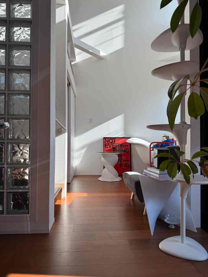 Natural tone entrance featuring white walls, brown wood flooring, cat tower and plants in a simple and clean setting