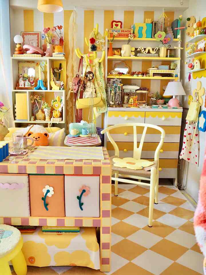 柔らかな黄色と白を基調とした小さな部屋、花柄の収納ボックスと多彩な装飾品が配置されたかわいいインテリア