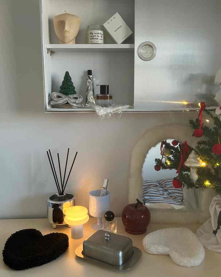 白とシルバーのトーンの金属製収納棚とテーブルが配置された、クリスマスの飾りと暖かな照明がある雰囲気のある空間