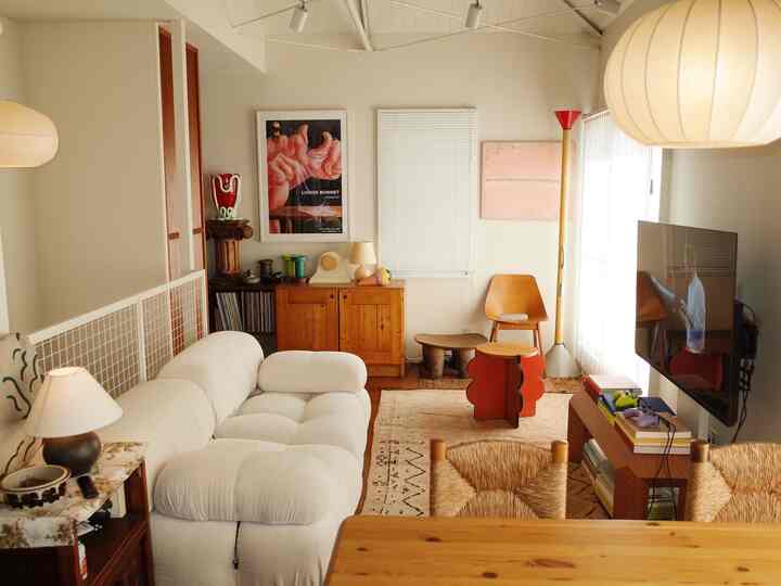 白と木目調が調和したミッドセンチュリーモダンのリビング、ヴィンテージ家具とアートが配置された雰囲気のある空間