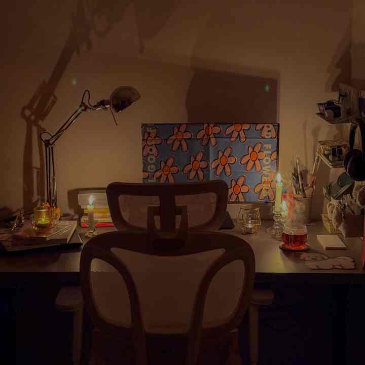 Cozy home office desk space for remote work featuring warm lighting and candles creating a calm atmosphere