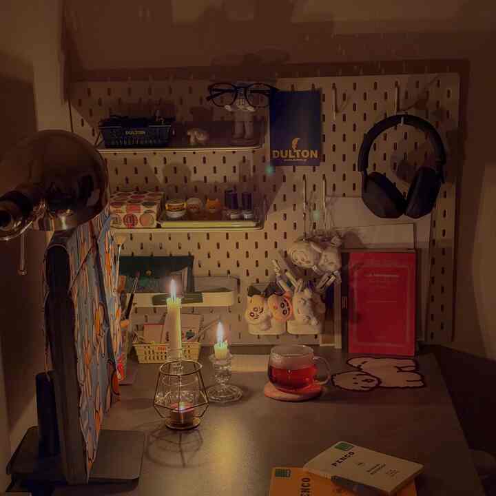 Warm brown-toned small room featuring a desk with computer, candles, and books creating a cozy remote work space