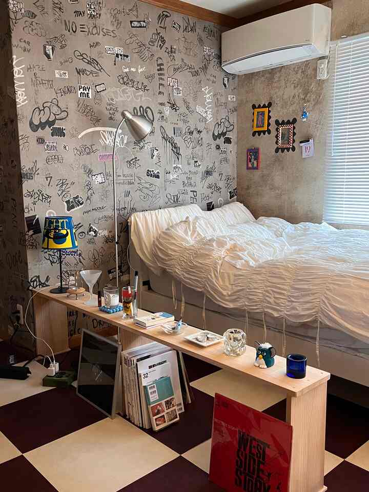 グラフィティ壁紙と白いベッドカバーが際立つ、チェック柄の床のヴィンテージスタイルの寝室