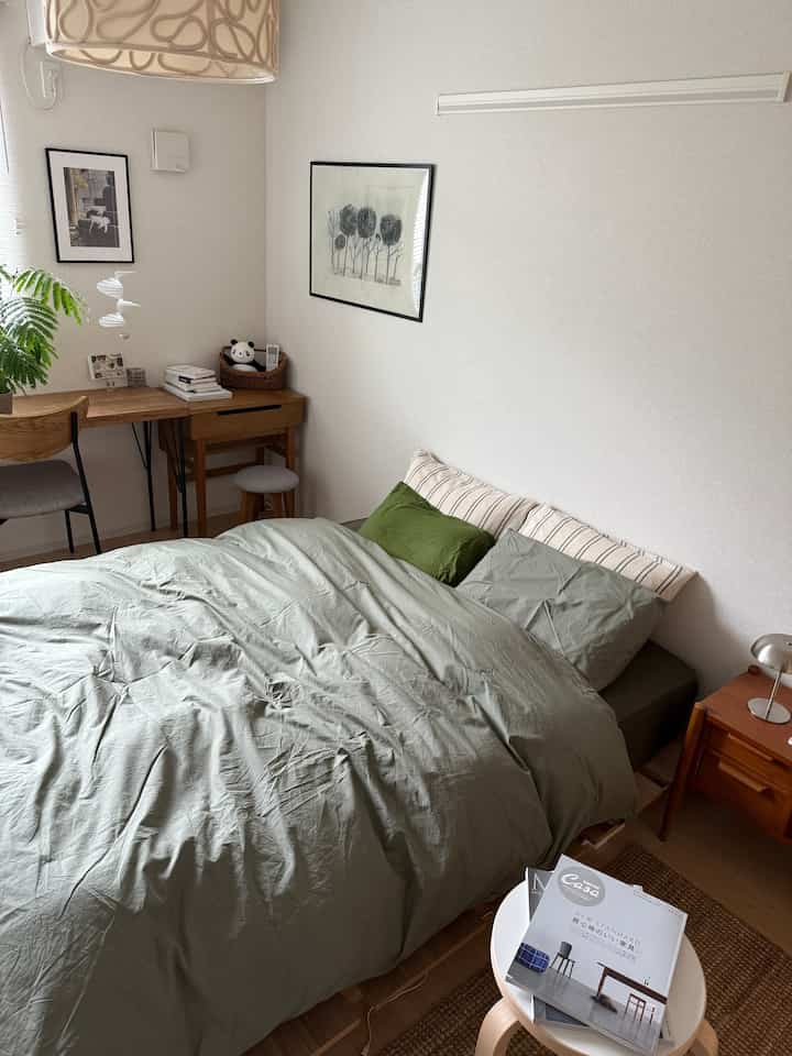 Natural-toned bedroom featuring simple wooden furniture and green bedding creating a cozy atmosphere