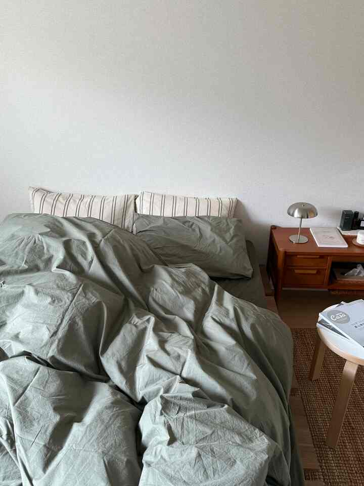 Olive green-toned bedroom featuring wooden side table and silver table lamp in a modern natural atmosphere