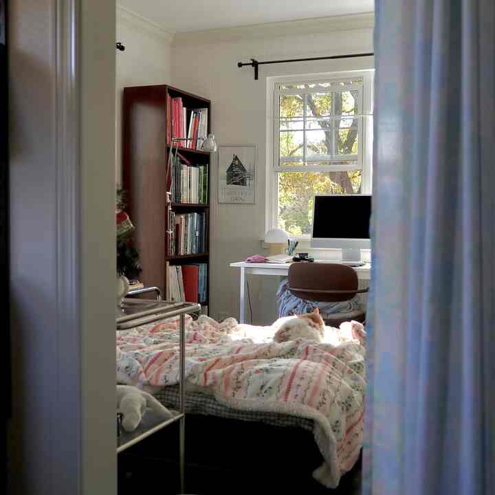 A white and brown bedroom featuring a window-side desk with computer and a cozy natural home office atmosphere