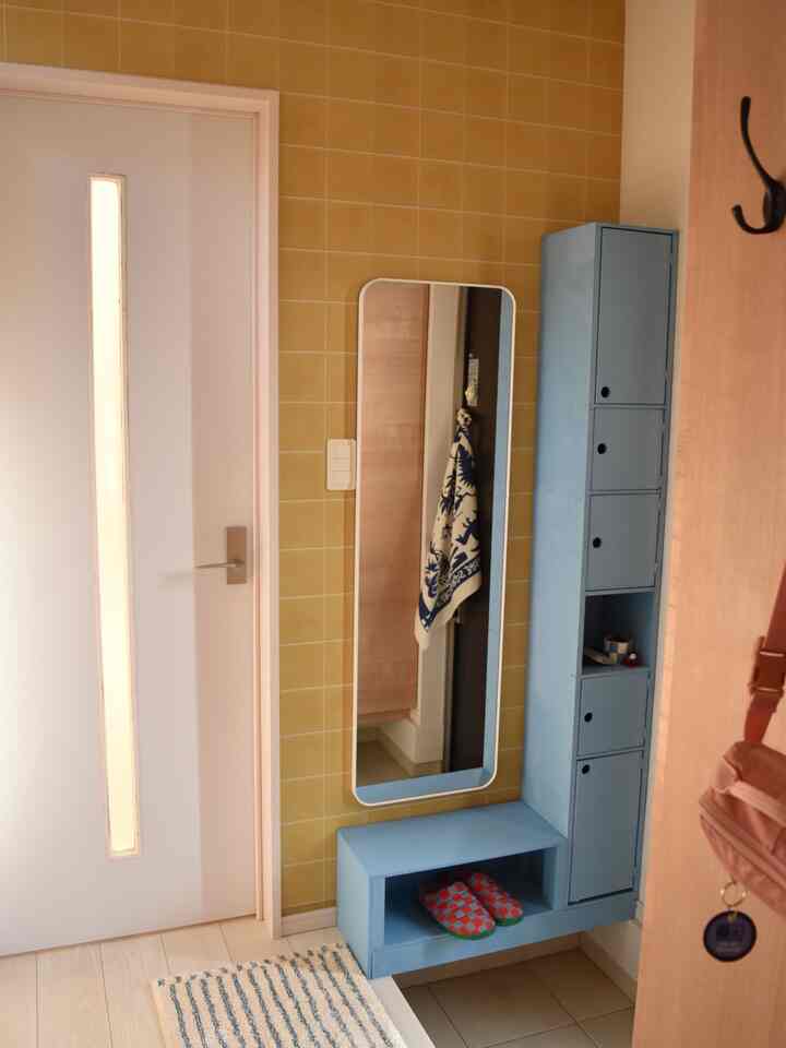 Entrance space with yellow tiled wall and blue storage cabinet, neat and functional atmosphere overall