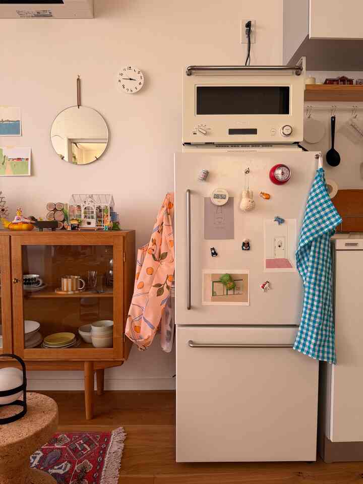 白と茶色の色調のキッチン、冷蔵庫と木製収納キャビネットが配置された雰囲気のある空間