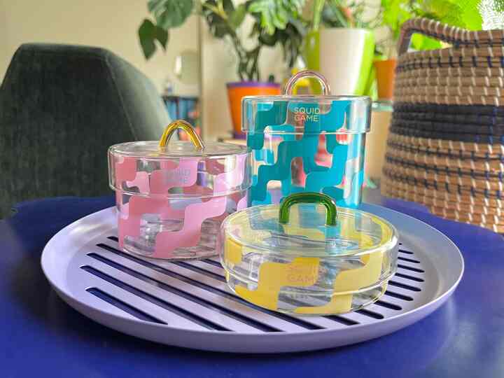 パステル調のピンク、黄色、緑のキャニスターがトレイに並べられた、ソファ横の居心地の良いリビング空間