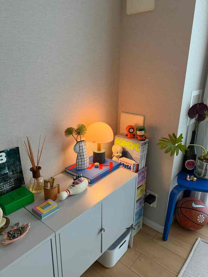 White and blue toned living room corner featuring a white cabinet, table lamp, and various decorative items with cozy atmosphere