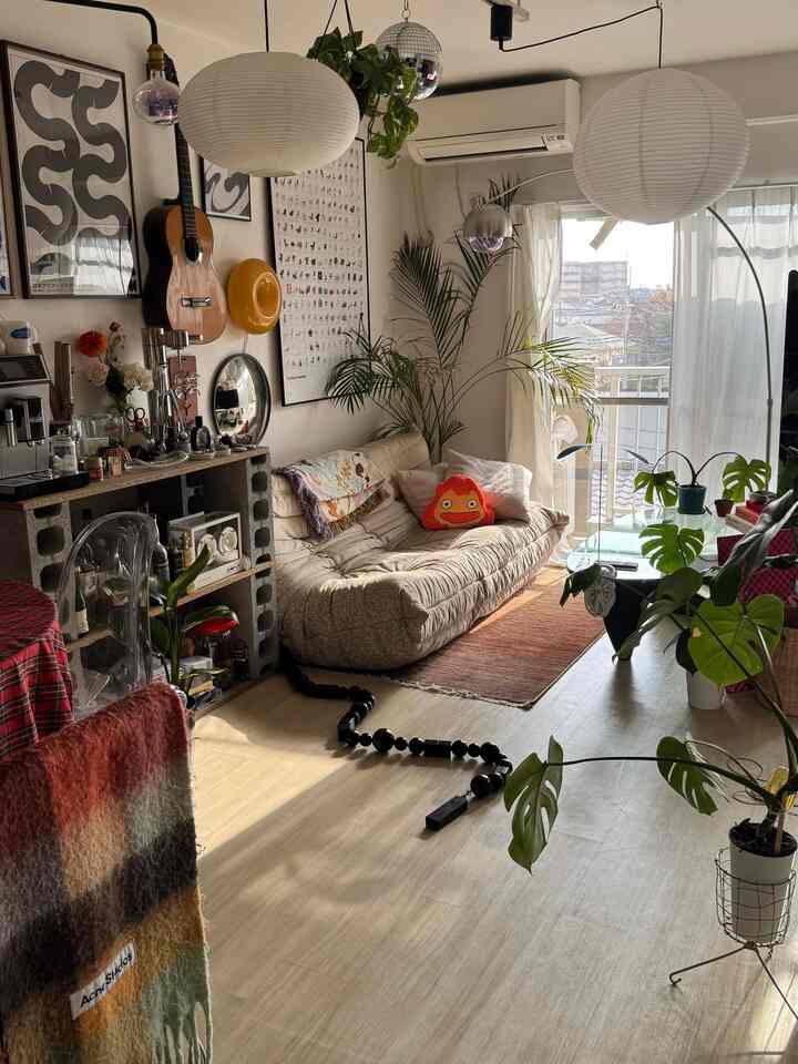 ベージュとグリーンの色調のリビング、自然な植物とミッドセンチュリーモダンのソファが配置された落ち着いた空間