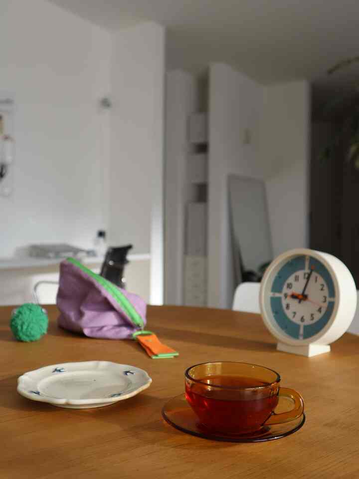 白と木目調のダイニング、木製テーブルの上にカップ、皿、時計が置かれた雰囲気のある空間