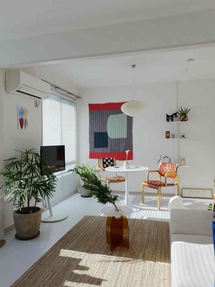 明るいホワイトトーンの壁とナチュラルなブラウンラグ、丸いダイニングテーブルとレザーのチェアが配置された北欧スタイルのリビング