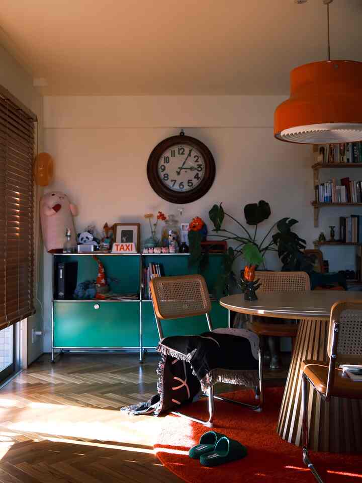Warm orange and wood tones blend in a Mid-Century Modern dining room featuring a round rug and pendant lighting creating a cozy atmosphere