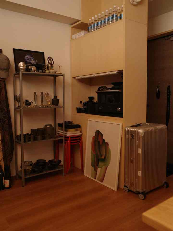 ナチュラルな色調の廊下横のキッチンスペース、メタルシェルフとキャビネットが調和するシンプルな空間