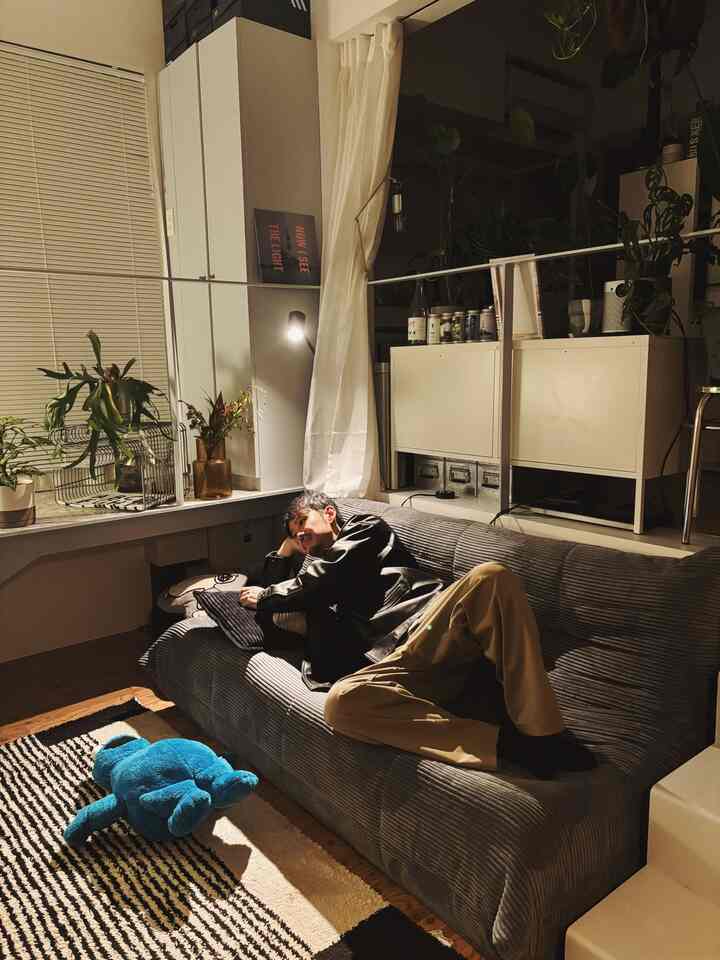 Cozy mid-century modern living room with gray sofa and white cabinet, featuring a blue plush toy and various plants in a simple setting