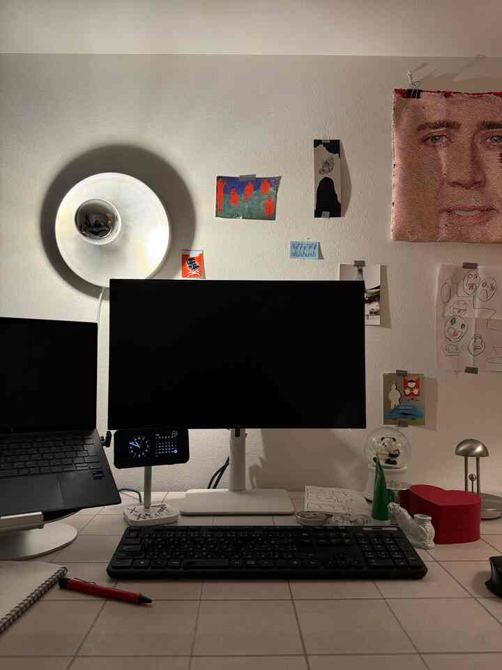Mid-Century Modern home office with white walls and silver wall sconce, a desk featuring monitor and keyboard setup