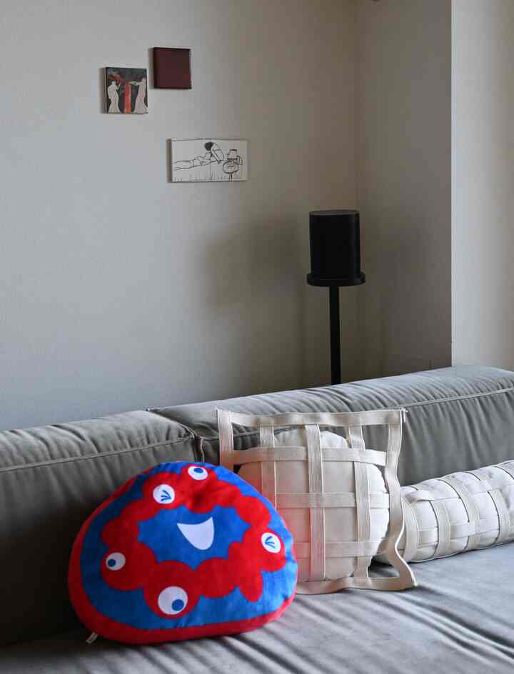 Modern living room with gray sofa and white cushions, featuring three framed artworks on the wall