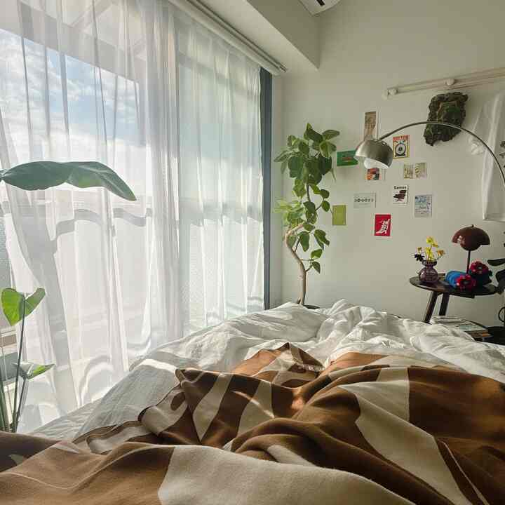 Warm natural-tone 8-tatami bedroom with sunlight-filled windows, mid-century modern lighting, and plants creating a cozy atmosphere