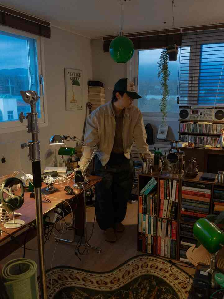 ダークブラウンの木目調が基調のヴィンテージ風書斎兼おうちカフェ、緑の照明と植物が印象的な空間