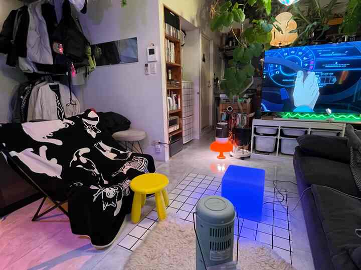 黒と白を基調としたリビング、ゲーム用大型テレビとソファ、猫柄のブランケットが配置された居心地の良いホームシネマ空間