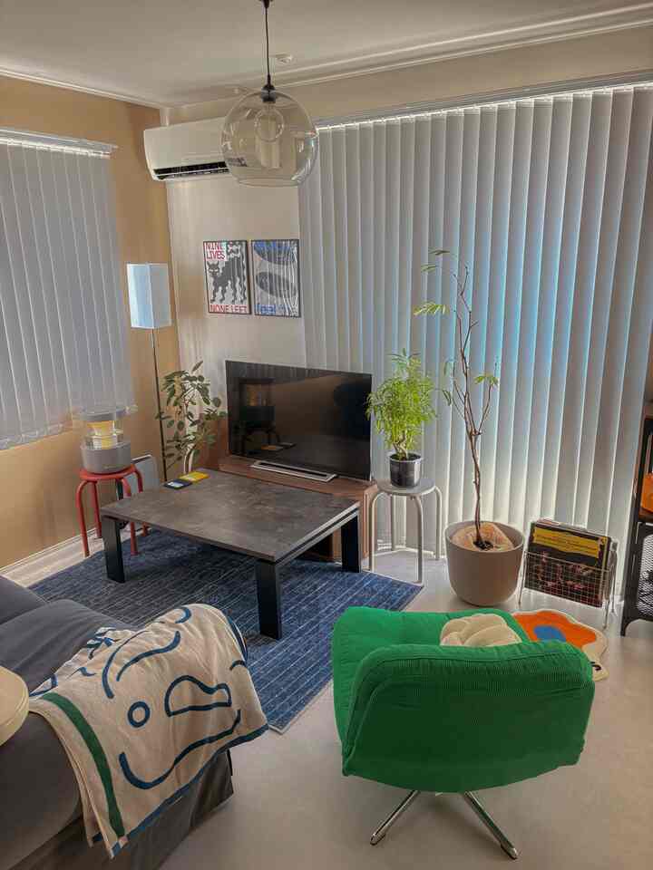 ナチュラルな色調にブルーとグリーンをアクセントにしたリビング、テレビとソファ、収納家具が配置された落ち着いた印象のインテリア