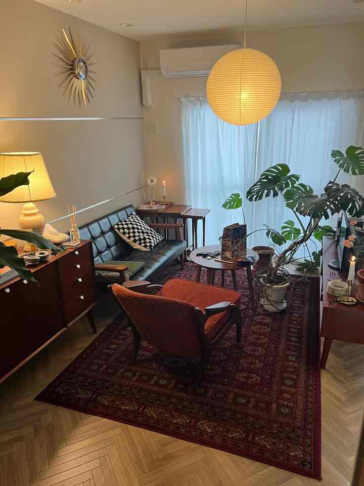 赤いラグと木製家具が配置されたミッドセンチュリーモダンのリビング、緑の植物が雰囲気を演出